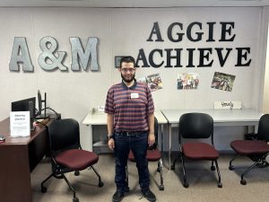 student posing in front of signage that says A&M AGGIE ACHIEVE